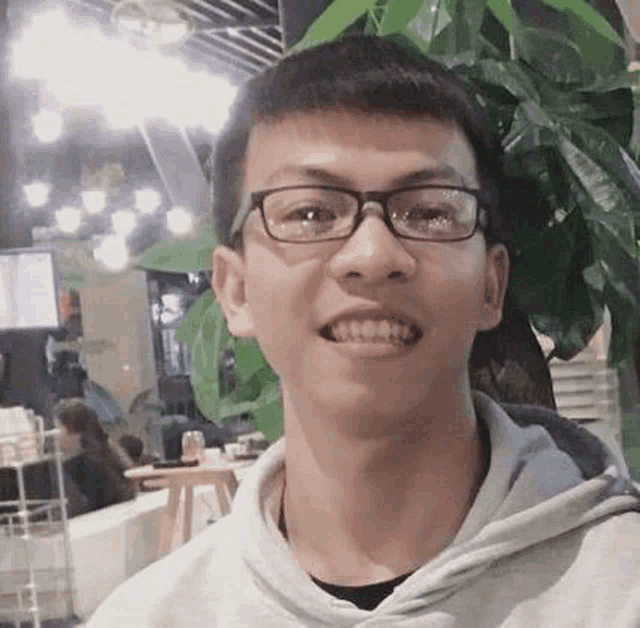 a young man wearing glasses and a hoodie is smiling for a picture .