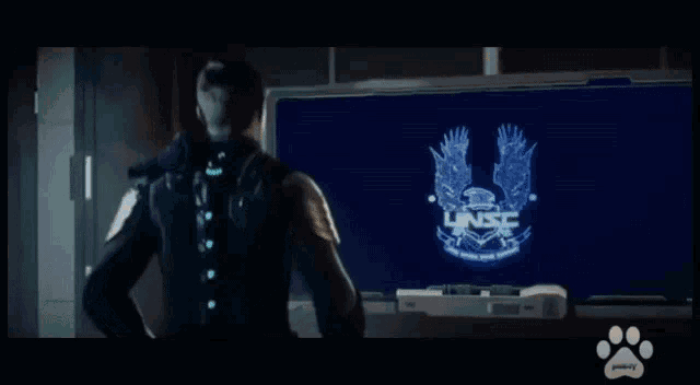 a man in a mask stands in front of a screen