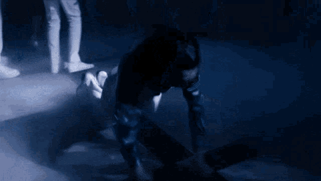 a person is doing a handstand on the floor in the dark