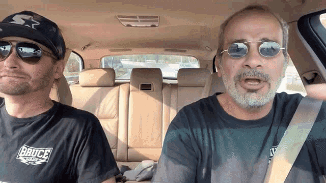 two men in a car one wearing a bruce t shirt