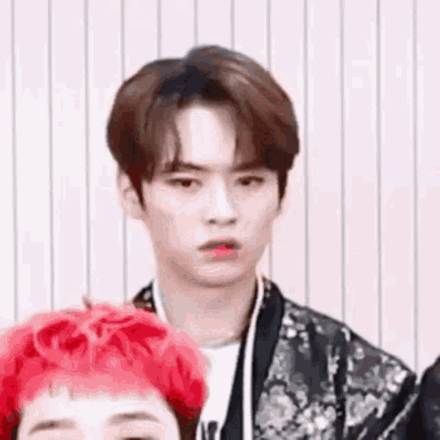 a young man with red hair is making a funny face while standing next to another young man .