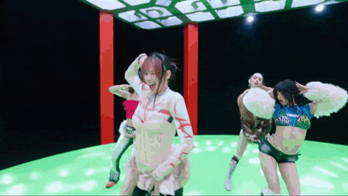 a group of women are dancing on a green stage