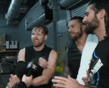 a group of wrestlers are standing next to each other in a room talking to each other .