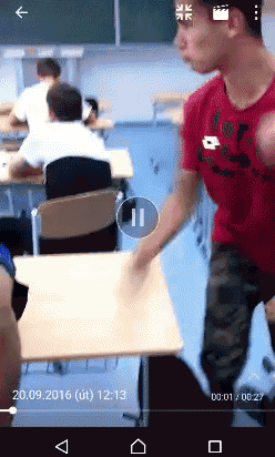 a man in a red shirt is standing in a classroom with a time stamp of 12:13