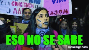 a girl with blue paint on her face is talking into a microphone with the words " eso no se sabe " above her