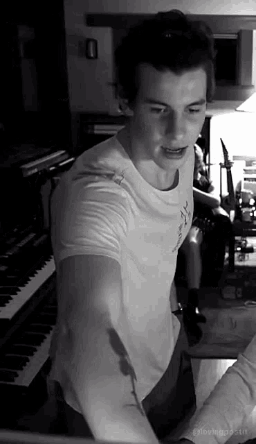 a man in a white shirt is standing in front of a piano