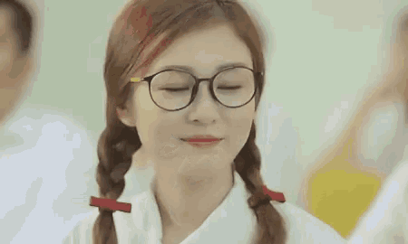 a girl wearing glasses and pigtails is making a funny face .