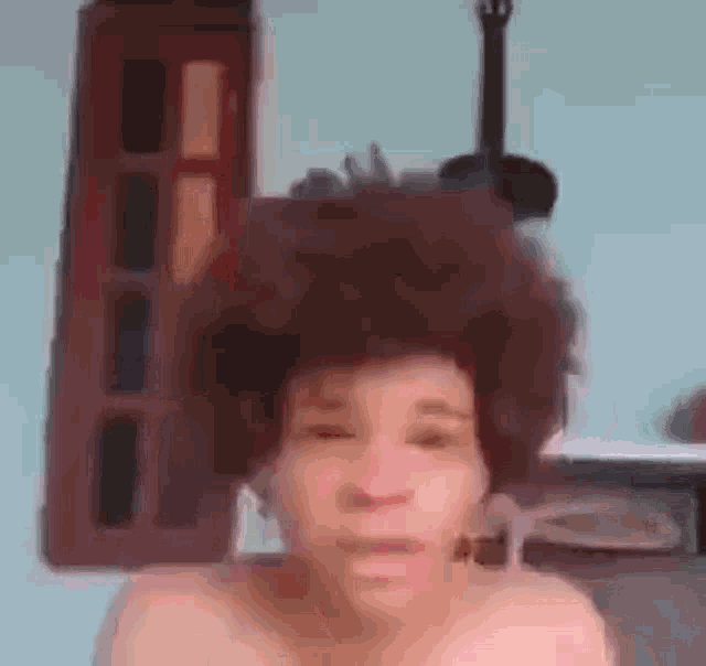 a man with a large afro is making a funny face in front of a building .