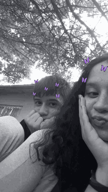 a black and white photo of a girl and a boy with butterflies on their faces