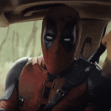 a man in a deadpool suit is sitting in a car