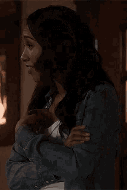 a woman in a denim jacket is making a funny face while holding her hand to her face .