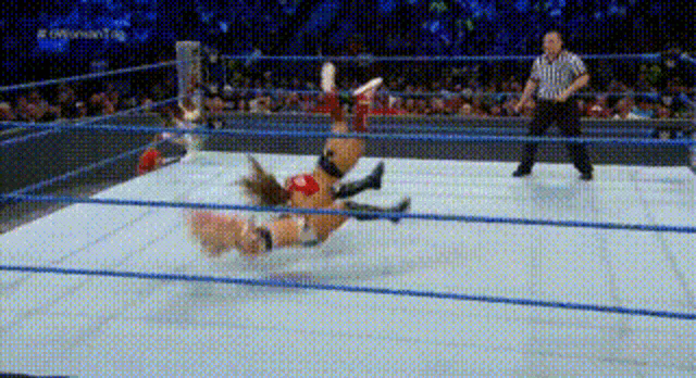 a wrestling match is going on in a ring and a referee is watching .