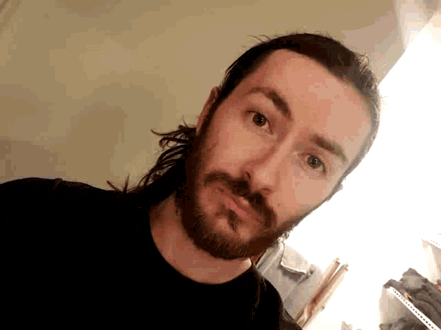 a man with long hair and a beard wearing a black shirt