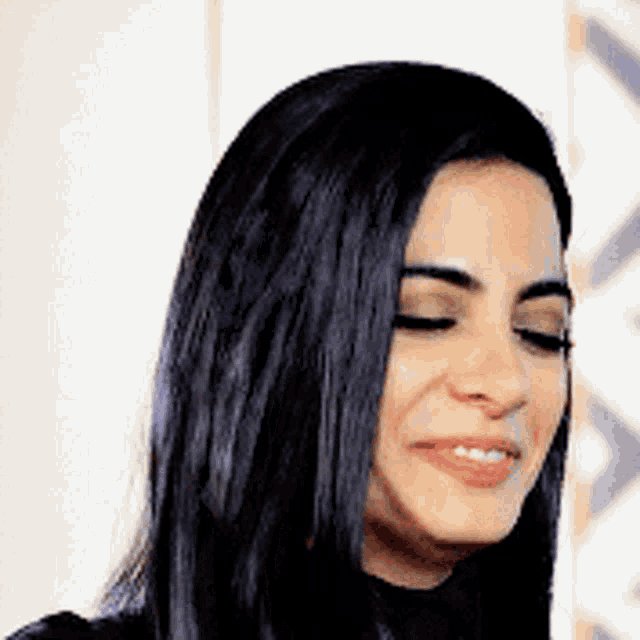 a woman with long black hair is smiling with her eyes closed .
