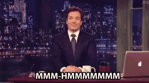 a man in a suit and tie is sitting at a desk with his eyes closed and says mmmm-hmmmmmm