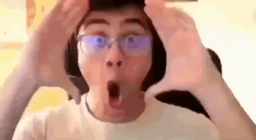 a man wearing glasses and headphones is making a surprised face while holding his head .