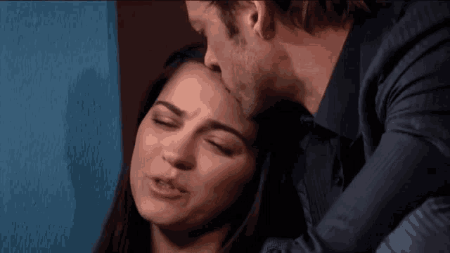 a man kisses a woman on the forehead in a close up
