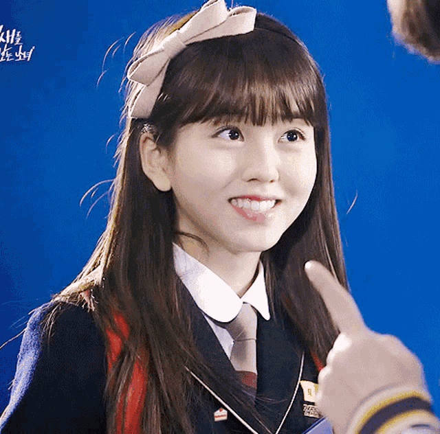 a girl wearing a headband with a bow on it smiles