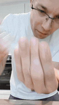 a man wearing glasses and a white shirt is holding a glass in his hand