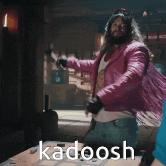 a man in a pink jacket is dancing with the word kadoosh written on the table