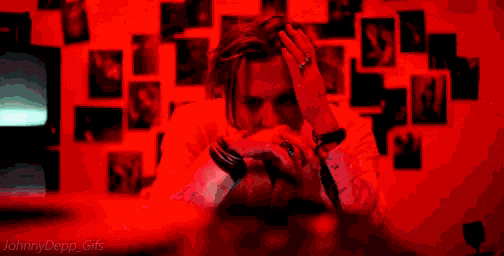 a person 's hand is reaching out towards a computer screen in a red light