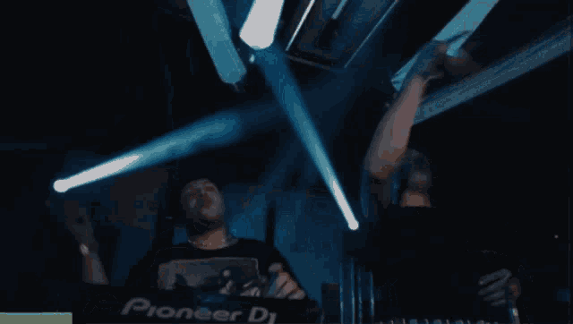 two men are dancing in front of a pioneer dj machine