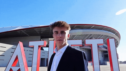 a man in a suit stands in front of a stadium that says atl