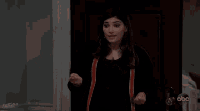 a woman is standing in front of a door with her arms outstretched and her mouth open .