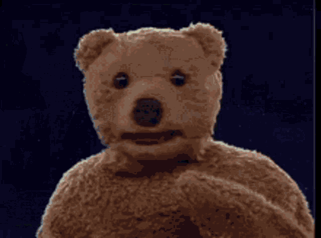 a man in a green cape stands next to a teddy bear holding a gift