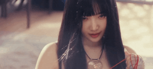 a young woman with long black hair is holding a red string in her hand .