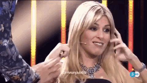 a woman with blonde hair and a necklace is being touched by a man on a stage .
