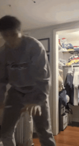 a man is dancing in a closet with clothes on the shelves