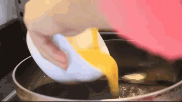 a person is pouring eggs into a pot of liquid