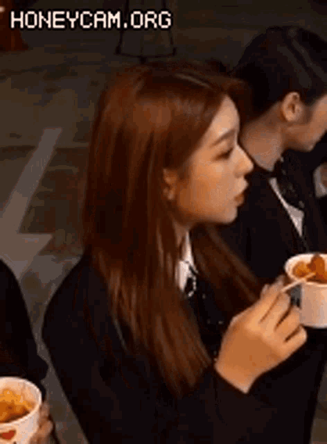 a woman is holding a bowl of food in her hand while sitting next to another woman .