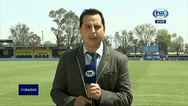 a man in a suit and tie holds a microphone in front of a fox sports logo