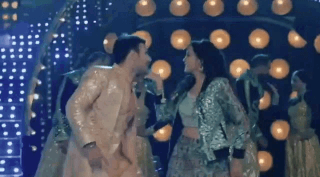 a man and a woman are dancing on a stage while singing into microphones .