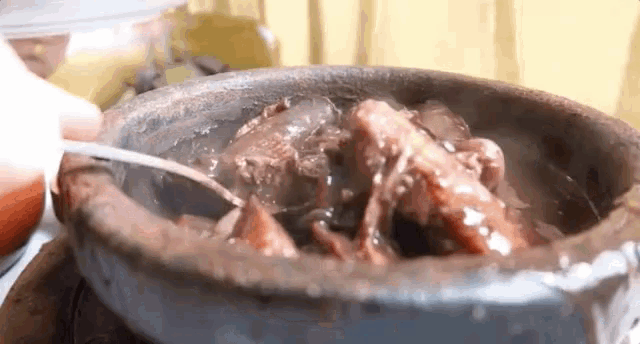 a person is pouring sauce into a bowl of meat .