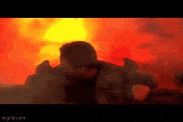 a man is standing in front of a fire in a dark room .