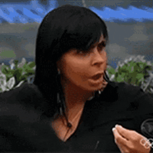 a woman with black hair is talking into a microphone while holding something in her hand .