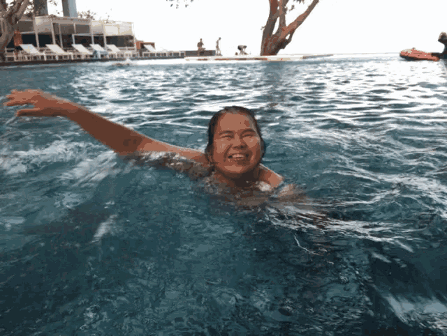 a woman is swimming in a swimming pool and smiling