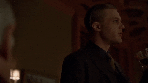 a man in a suit and tie is standing in a dark room with another man .