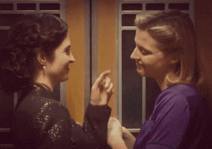 a woman in a purple shirt is touching another woman 's face