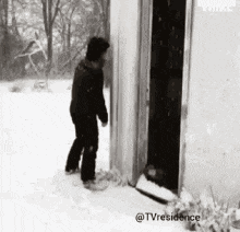 a black and white photo of a man standing in the snow .