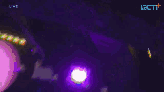 three girls in white dresses are dancing on a stage with the word live in the upper right corner