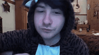 a young man wearing a cat costume is making a funny face while looking at the camera .