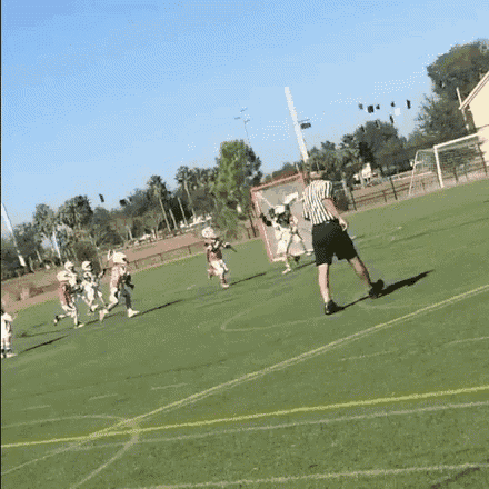 a referee is standing on a field watching a lacrosse game being played