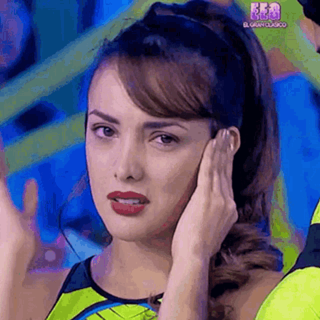 a woman is covering her ear with her hand while wearing a green shirt .