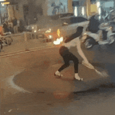 a group of people are standing around a fire in the middle of the street .
