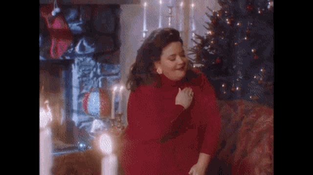 a woman in a red sweater is sitting on a couch with a christmas tree in the background