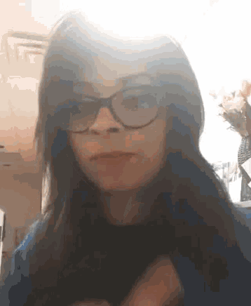 a woman wearing glasses and a blue shirt is making a face